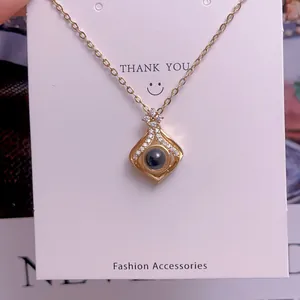 Detailaufnahme einer Goldkette mit Projektionsanhänger, schwarzem Stein und Kristallen