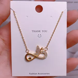 Golden infinity heart pendant necklace with shimmering zircons on white display card