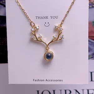 Detail of gold reindeer antler pendant with small white zircons and a grey projection stone