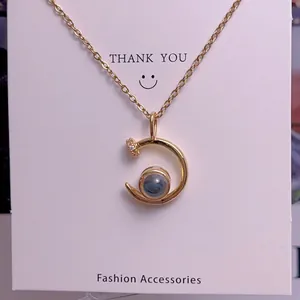 Detail view of gold chain necklace with a crescent moon pendant and dark blue projection stone