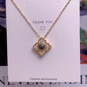 Detail of gold clover necklace with white crystals and projection stone on backing card