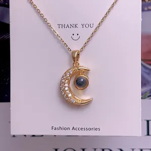 Detailed view of a gold crescent moon pendant set with zircons and a central grey stone