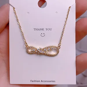 Macro shot of gold infinity necklace pendant with sparkling zircon on a white gift card