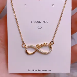 Detailed close-up of a gold infinity necklace with Berica lettering on display card