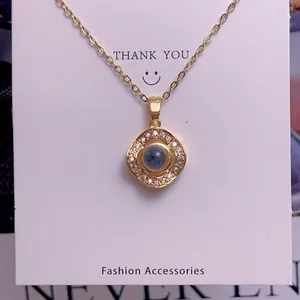 Detail of gold pendant necklace with square zircon border on a white display card