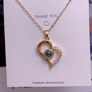 Detail of gold heart projection necklace with blue stone and sparkling zircon accents