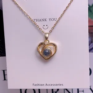 Macro shot of gold heart pendant with gray projection stone on a white display card