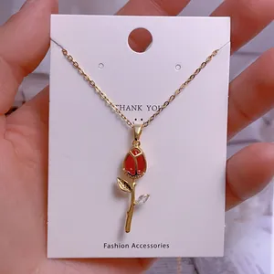 Détail du collier pendentif tulipe dorée avec bouton rouge et feuille en cristal