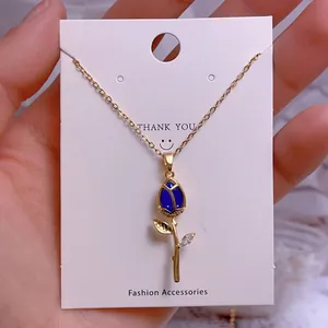 Détail du pendentif tulipe dorée avec pétale bleu et zircon blanc sur carte