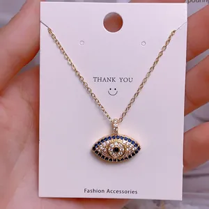 Detailaufnahme des goldenen Evil Eye Anhängers mit blau-weißen Zirkonia an einer Kette