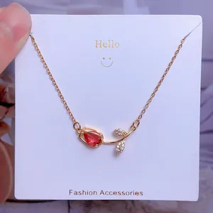 Gros plan d'un pendentif tulipe doré avec gemme rouge et feuilles serties de cristaux