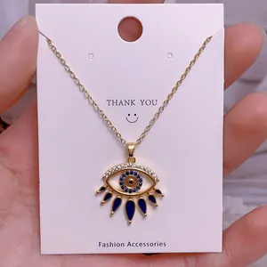 Detail eines goldenen Evil Eye Anhängers mit blau-weißen Kristallen an einer Kette