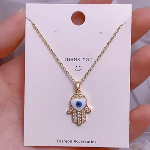 Detail von Hamsa-Anhänger in Gold mit weißem Herz und blauem Auge an einer Halskette