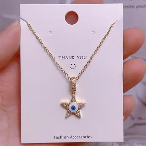 Detail des sternförmigen Evil-Eye-Anhängers in Gold mit weißen Kristallen und blauer Emaille