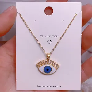 Detail der Evil-Eye-Halskette mit blauem Emaille und goldenen Wimpern auf Karte