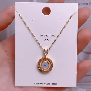 Detailaufnahme der goldenen Evil Eye Halskette mit Love-Gravur auf eleganter Displaykarte