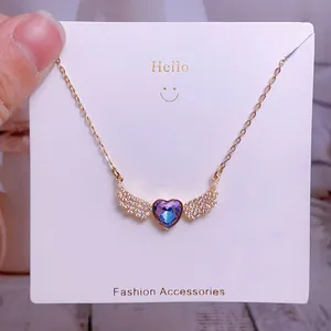 Détail du collier cœur ailé avec cristal dégradé violet sur une carte de bijoux