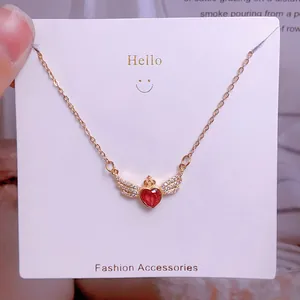 Détail du collier en titane doré avec pendentif cœur rouge et ailes d'ange