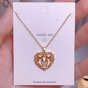 Primer plano del collar con colgante de corazón dorado con letras MM y cristales brillantes
