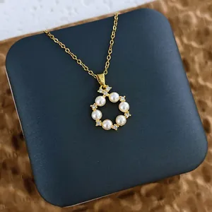 Détail du collier doré avec pendentif ajouré rond orné de perles blanches et de zircons