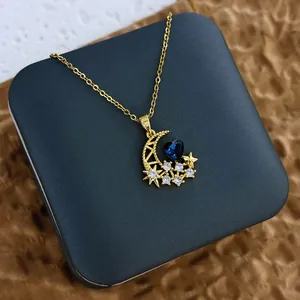 Vue détaillée du pendentif lune dorée avec zircon bleu sur une boîte à bijoux élégante