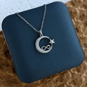 Détail du pendentif lune argentée et infini avec zircons sur un écrin bleu élégant