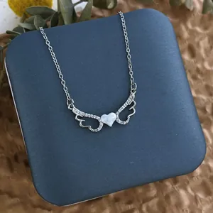 Détail du collier ailes d'ange en argent avec pendentif cœur en zircon sur boîte cadeau