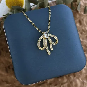 Détail du collier noeud doré avec micro-pavage de zircons et cristal dans un coffret bleu