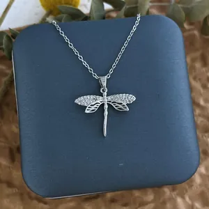 Détail du collier libellule argenté avec zircons blancs sur une élégante boîte cadeau