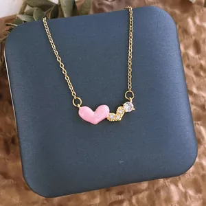 Détail du collier en acier titane doré avec pendentif cœur rose et zircons