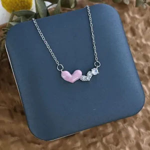 Détail du pendentif cœur en émail rose avec zircone sur une fine chaîne argentée