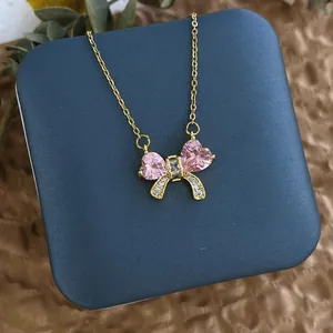 Détail d'un collier pendentif nœud rose en or dans un écrin de bijoux bleu élégant