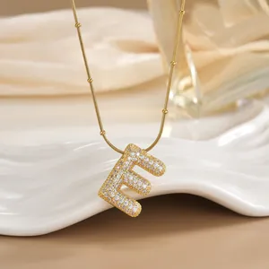 Macro shot of gold-plated letter E pendant with cubic zirconia on a satellite chain