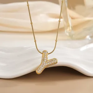 Macro detail of gold letter Y necklace featuring micro-pave cubic zirconia on satellite chain