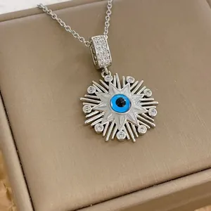 Macro shot of silver sunflower evil eye pendant with blue resin and zircon stones