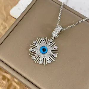 Detailed macro view of evil eye sunburst pendant necklace with blue crystal and white rhinestones
