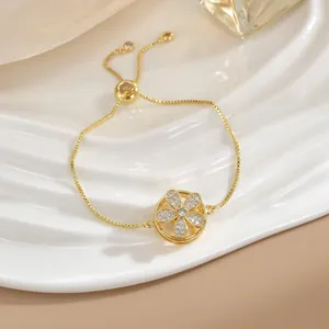 Dettaglio del bracciale a fiore dorato regolabile con zirconi su vassoio in ceramica