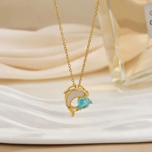 Dettaglio della collana delfino dorata con gemma a cuore blu e inserto in madreperla