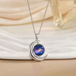 Detail van sterrenstelsel maan hanger aan zilveren ketting op een witte keramische schaal