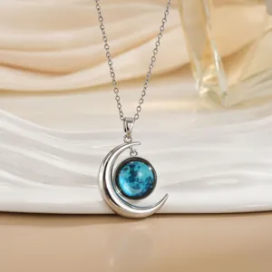 Detail van zilveren halve maan ketting met een blauwe planeetsteen op satijn