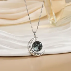 Detailopname van een zilveren ketting met maan en ster hanger op een wit dienblad