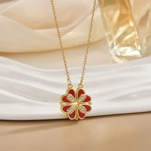 Elegant gold clover necklace with red heart petals on white ceramic jewelry tray