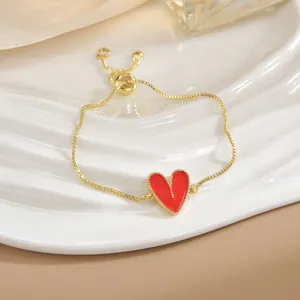 Dettaglio del bracciale dorato regolabile con cuore in smalto rosso e bordi perlati