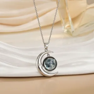 Detail van zilveren halve maan ketting met maanstructuur hanger op wit dienblad