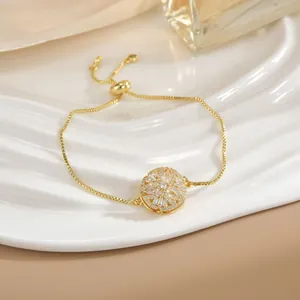 Dettaglio di un bracciale dorato regolabile con ciondolo a fiore in zircone su vassoio