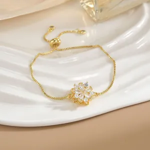 Dettaglio del bracciale a catena dorata con ciondolo a fiore in zircone e chiusura scorrevole