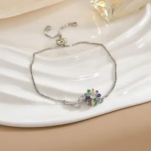 Primo piano di un bracciale a fiore rotante con zirconi colorati su vassoio ceramico