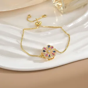 Dettaglio del bracciale bolo dorato con ciondolo a fiore in zircone colorato su catena