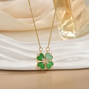 Detail view of heart-shaped clover necklace on silk backdrop with elegant perfume bottle