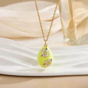 Macro shot of yellow egg pendant necklace with floral enamel in 18K gold finish